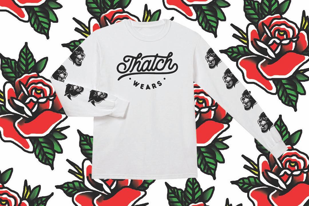 White long-sleeve organic cotton tee with black "Thatch Wears" logo on the front and black panther head prints down both.